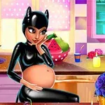 En gravid kvinde iført en sort dragt sidder ved et køkkenbord med farverige dekorationer omkring sig