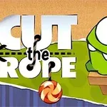 En grøn, tegneserieagtig figur med store øjne sidder på en træplatform ved siden af et slikstykke, mens teksten Cut the Rope er i baggrunden