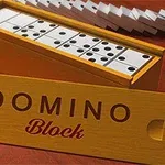 En æske med dominobrikker og en træplade mærket DOMINO Block på en rød overflade