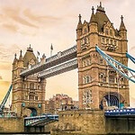 Tower Bridge i London ved solnedgang med vandet i forgrunden og bygninger i baggrunden