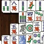 Et udsnit af mahjong-brikker med forskellige symboler og farver arrangeret på en træbaggrund