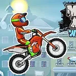 En rytter i orange dragt på en motocrosscykel kører i en sneklædt by med et dekoreret juletræ i forgrunden