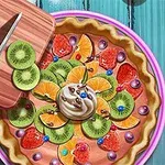 En farverig frugttærte med skiver af kiwi, appelsin, jordbær og flødeskum i midten, ved siden af et skærebræt med en kniv
