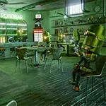 Industrielt indrettet bar med robotter, der sidder ved borde og en bar med neonskilt