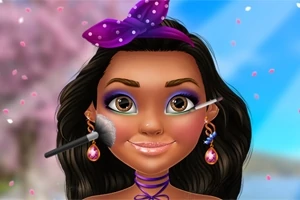 En kvinde med langt sort hår og farverig makeup får lagt makeuppen med pensler foran en sløret baggrund med lyseblå og lyserøde nuancer