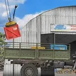 En lastbil parkeret foran et lager med et skilt CARGO DELIVERY, mens en kran løfter en rød container
