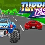 En blå monstertruck med ordet BIGFOOT og en rød sportsvogn kører side om side på en vej med træer i baggrunden, mens teksten TURBO TASTIC ses øverst i billedet